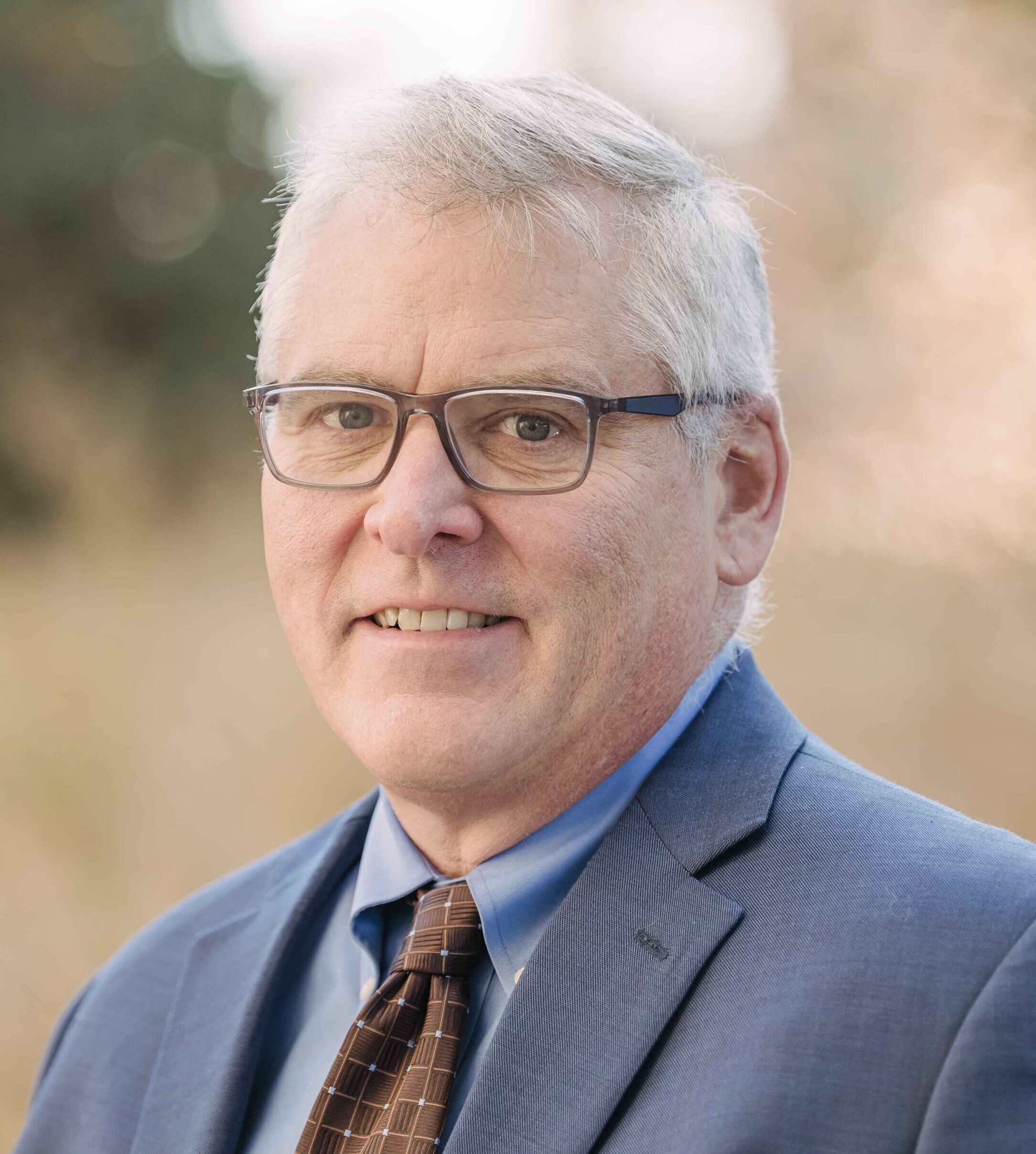 Bryan Casey in a grey suit with blue button-down shirt and red checkered tie